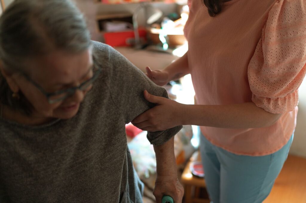 helping elder to stand up Compassionate caregiver helps elderly woman with mobility at home, offering caring support.