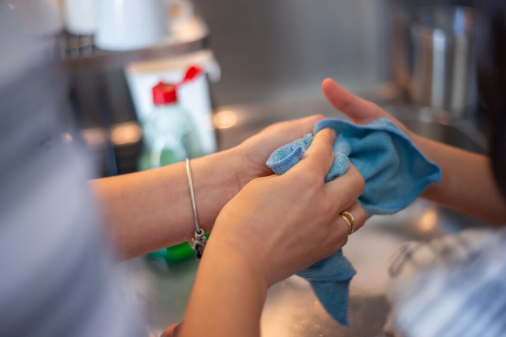 Cleaning participant house Detailed image of two people cleaning using a blue cloth indoors. Perfect for hygiene concepts.